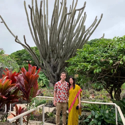 Amy and James standing in front of a large cactus tree at Sanchita and Forrest's wedding in Kauai